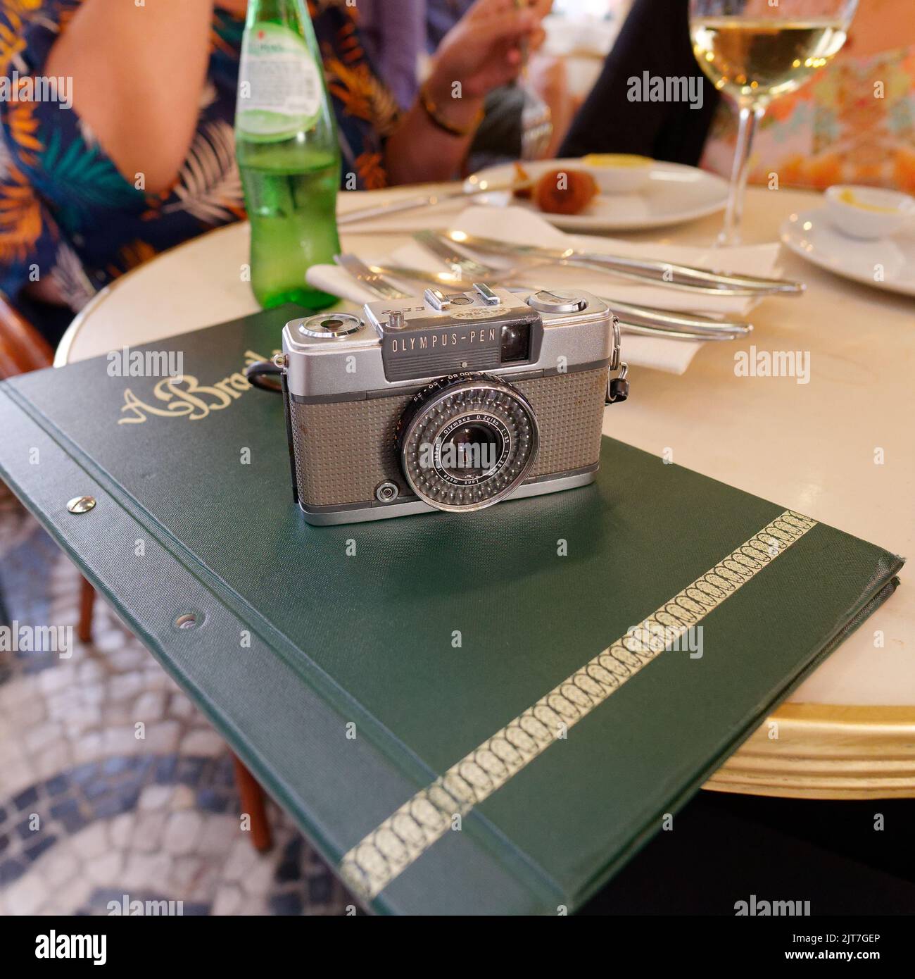 Reto styled Olympus Pen film camera on top of a menu on a table in the famous A Brasileira coffe shop in the Chiado neighbourhood of Lisbon Stock Photo