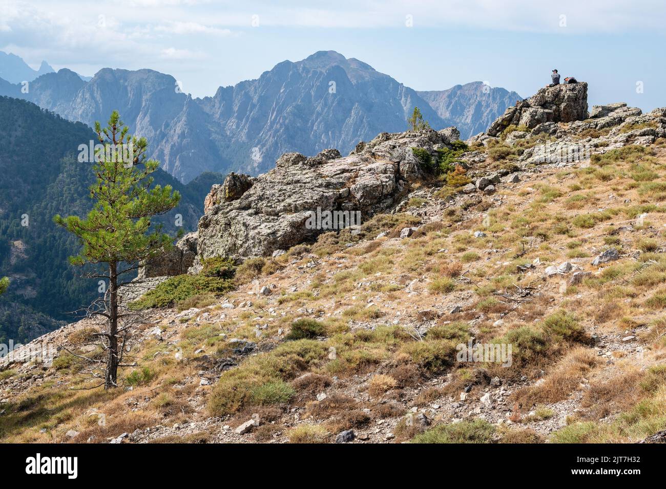 Hiker taking a break on the GR20 facing a magnificent panorama, Corsica, France Stock Photo