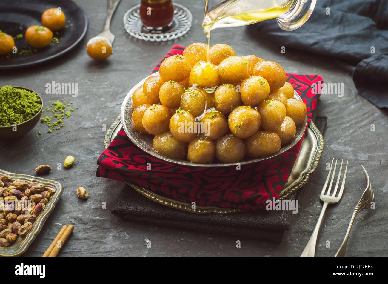 Arabic Cuisine; Pouring honey on Middle Eastern traditional dessert