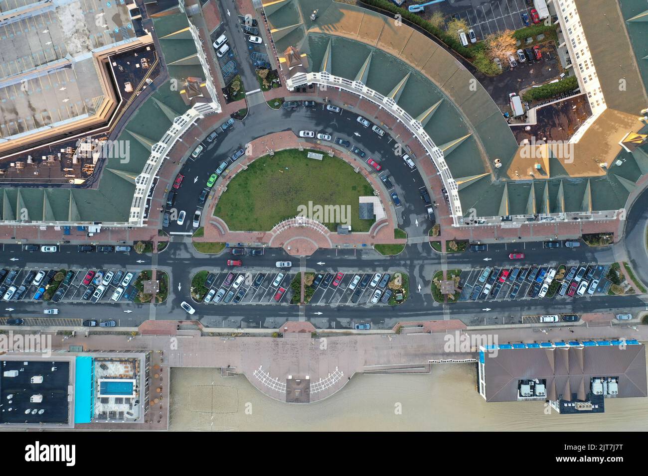 An aerial view of a city with roads, parking lots and cars is New