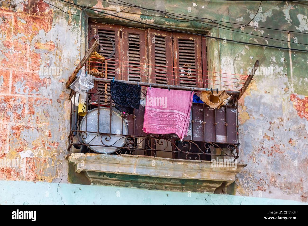 Clothes drying in the railing of a balcony. The exterior wall of the building is weathered and lacking maintenance. The scene is common in the capital Stock Photo