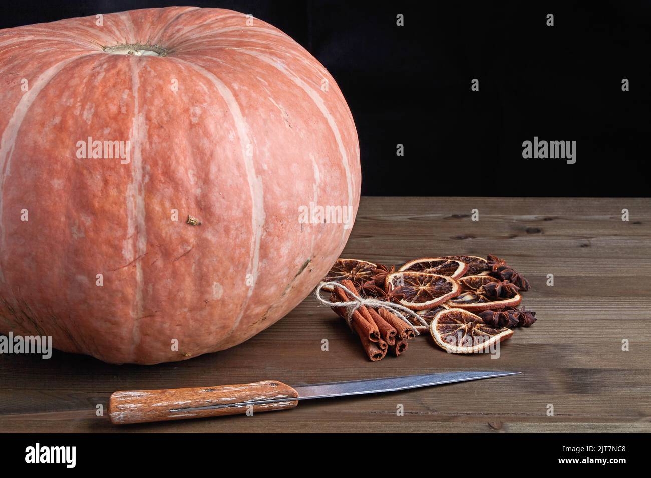 Beautiful big orange pumpkin and dried spices for making jam on a wooden table on a dark background Stock Photo
