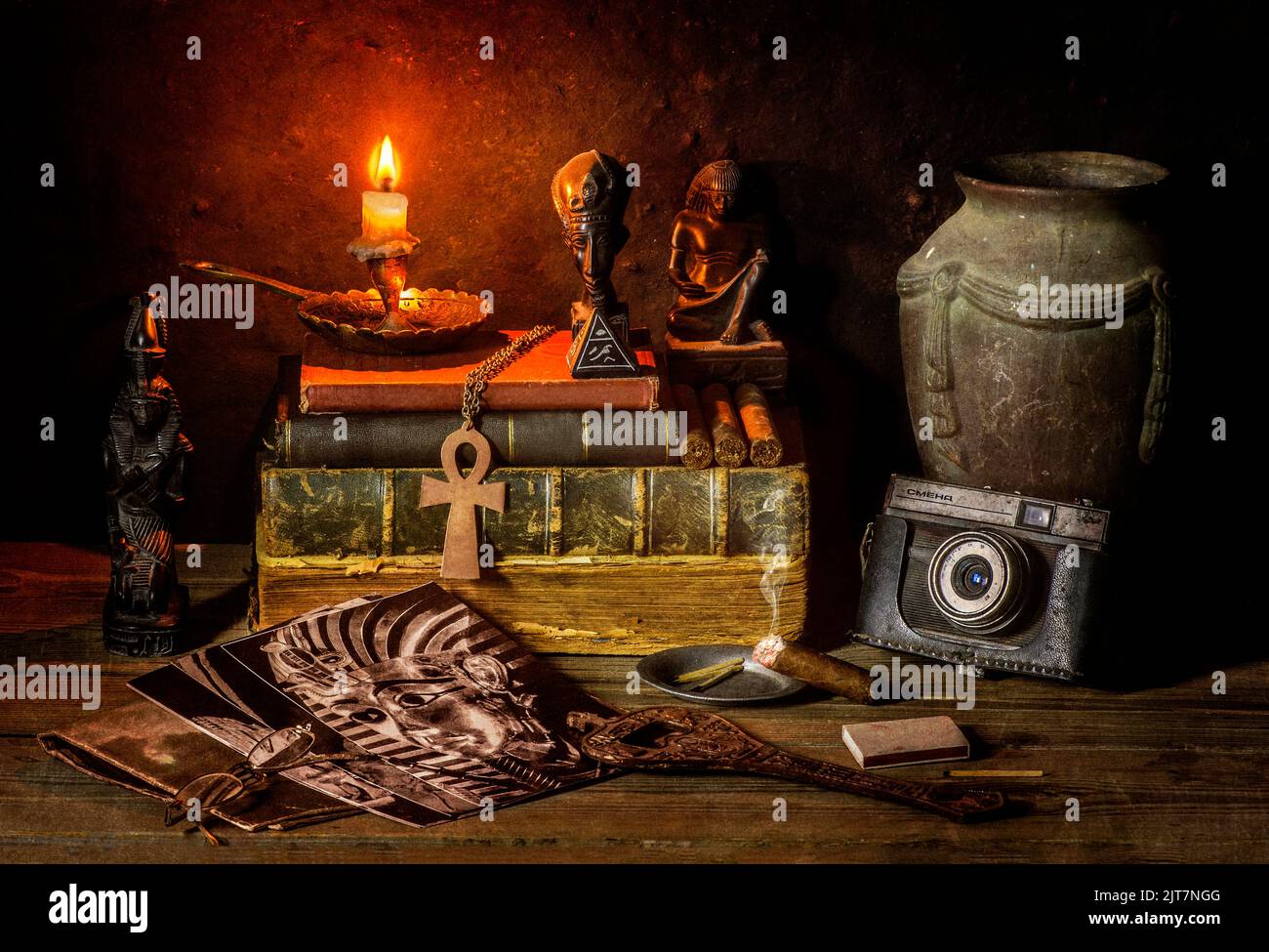 Classic still life with vintage books placed with old jar, illuminated candle, camera, old pictures, cigar and some ancient Egyptian sculptures. Stock Photo
