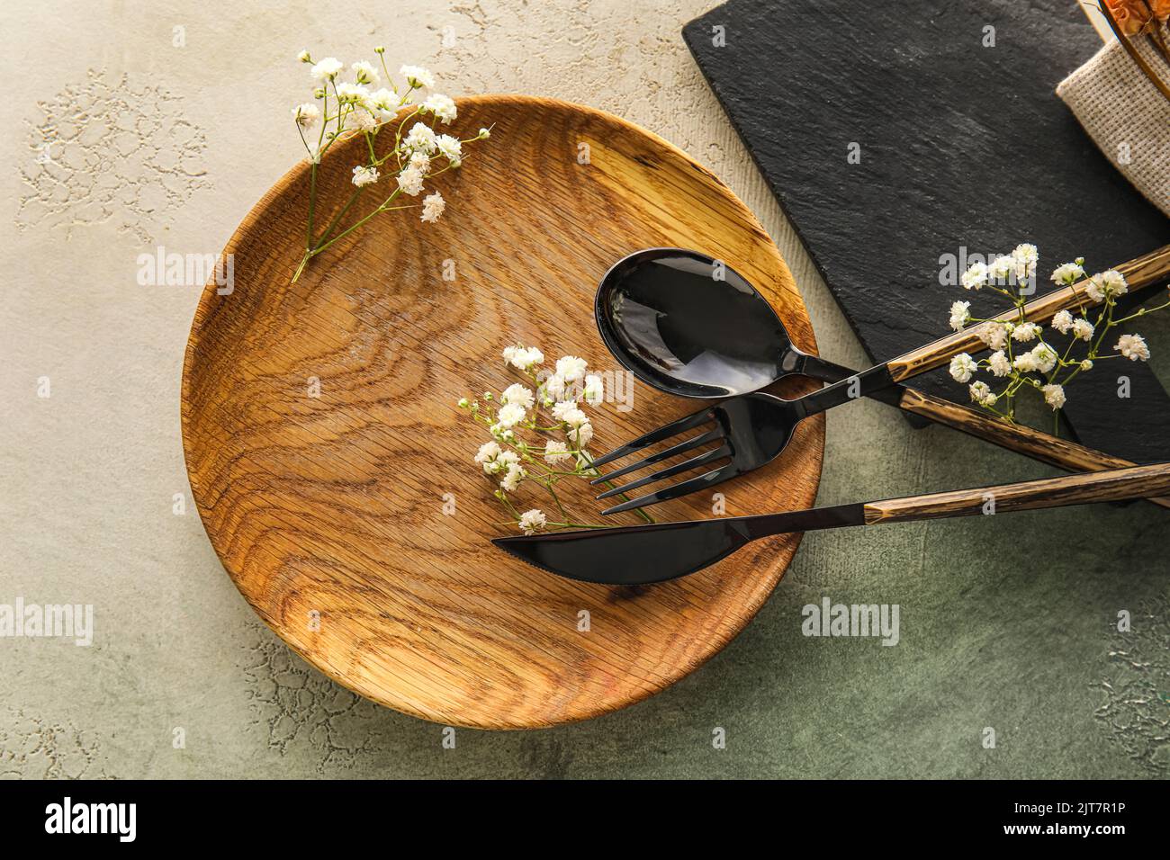 Table setting with wooden plate and gypsophila flowers on white and