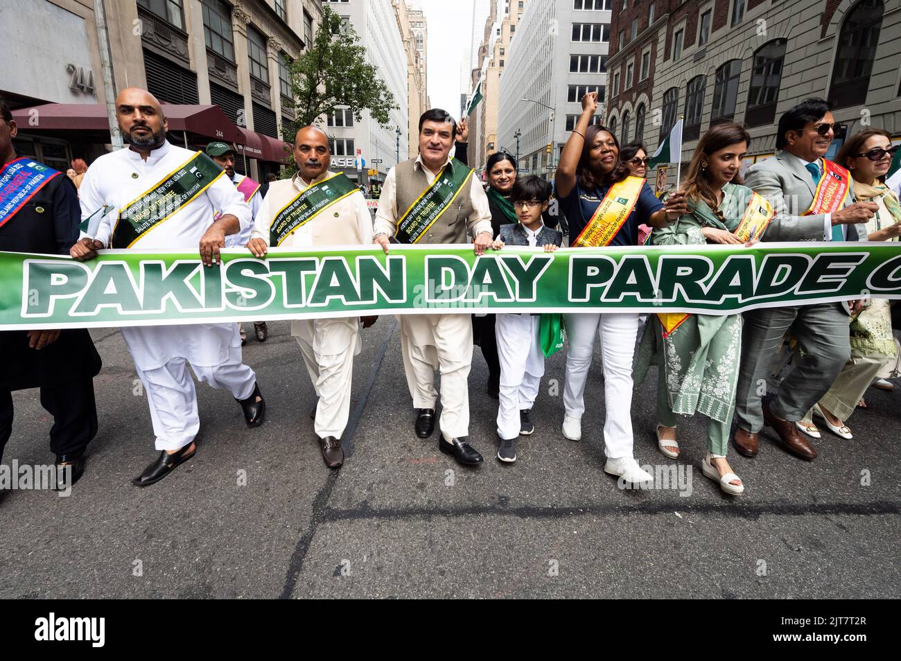 People marching with a banner saying "Pakistan Day Parade" at the New