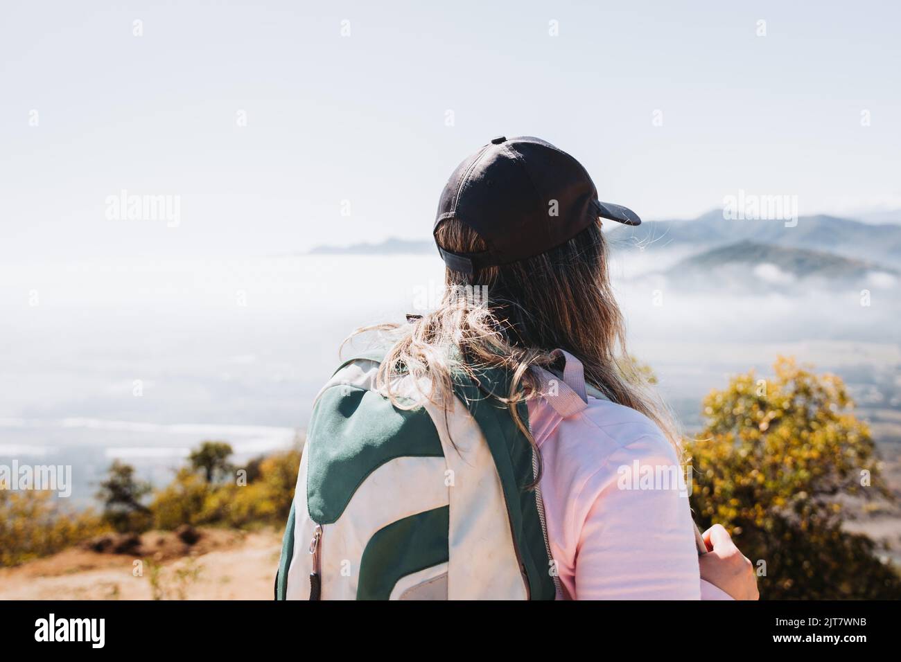 Rear view young latin woman with backpack on, contemplating view from