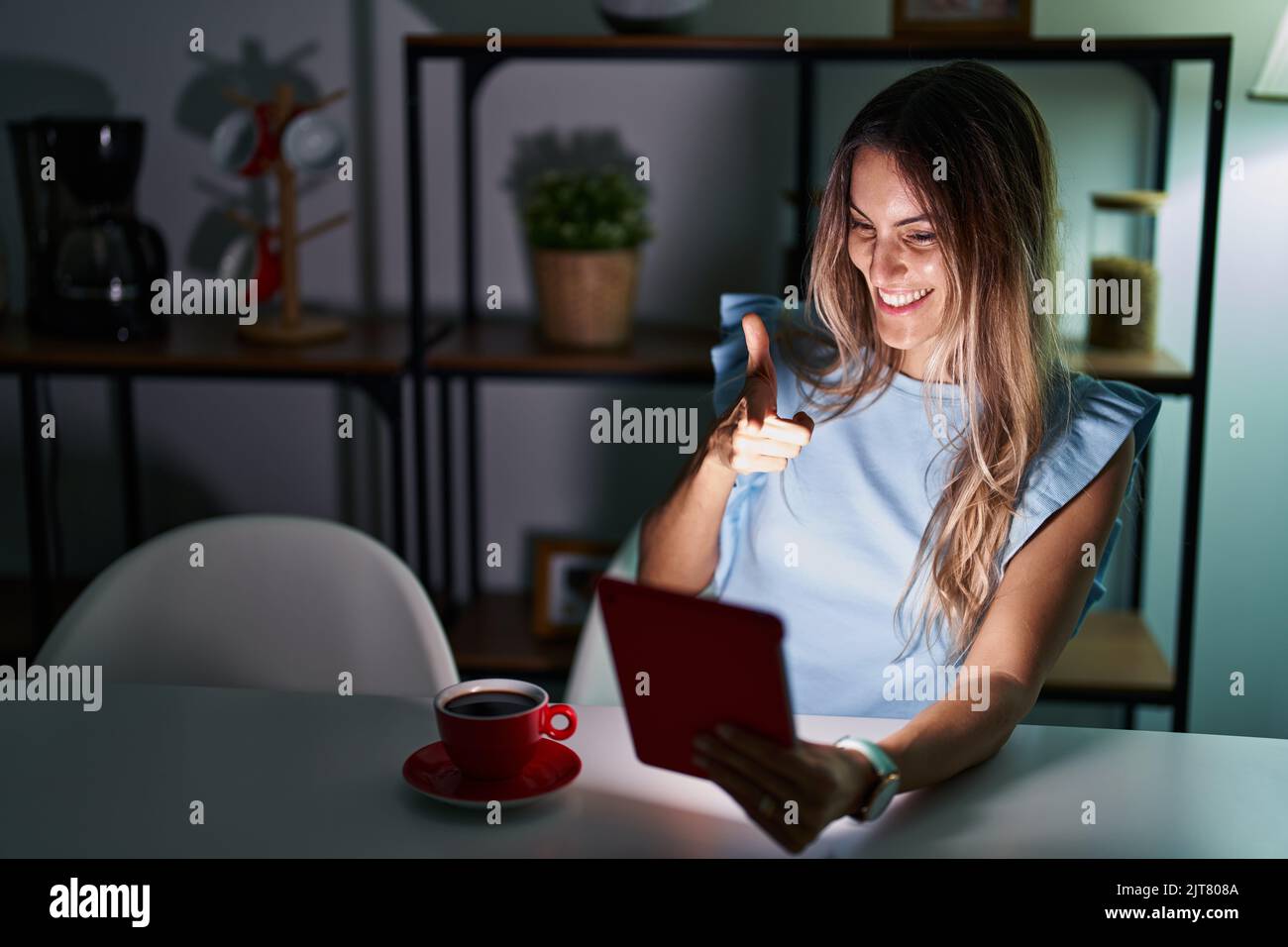 Young hispanic woman using touchpad sitting on the table at night ...