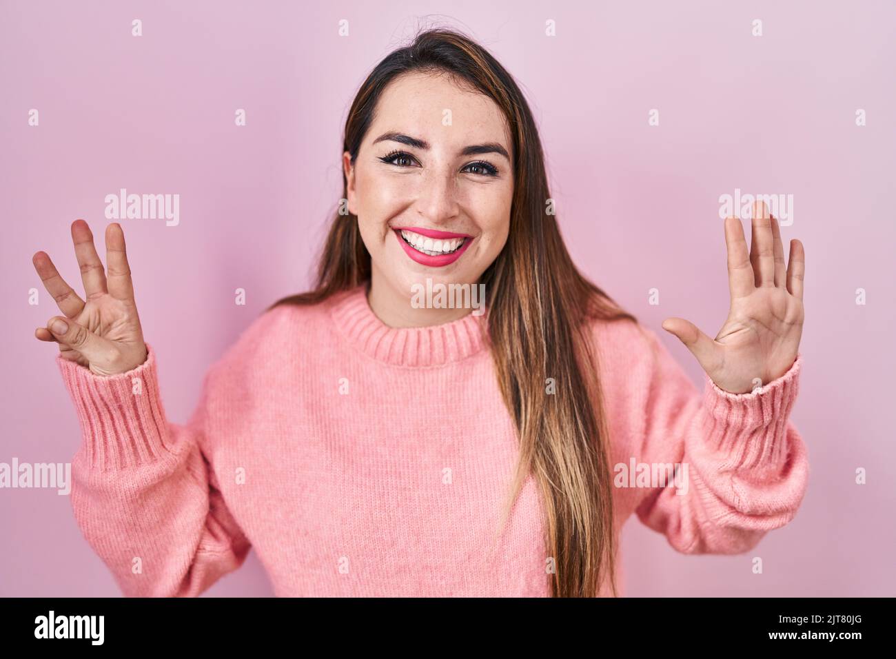 Young hispanic woman standing over pink background showing and pointing ...