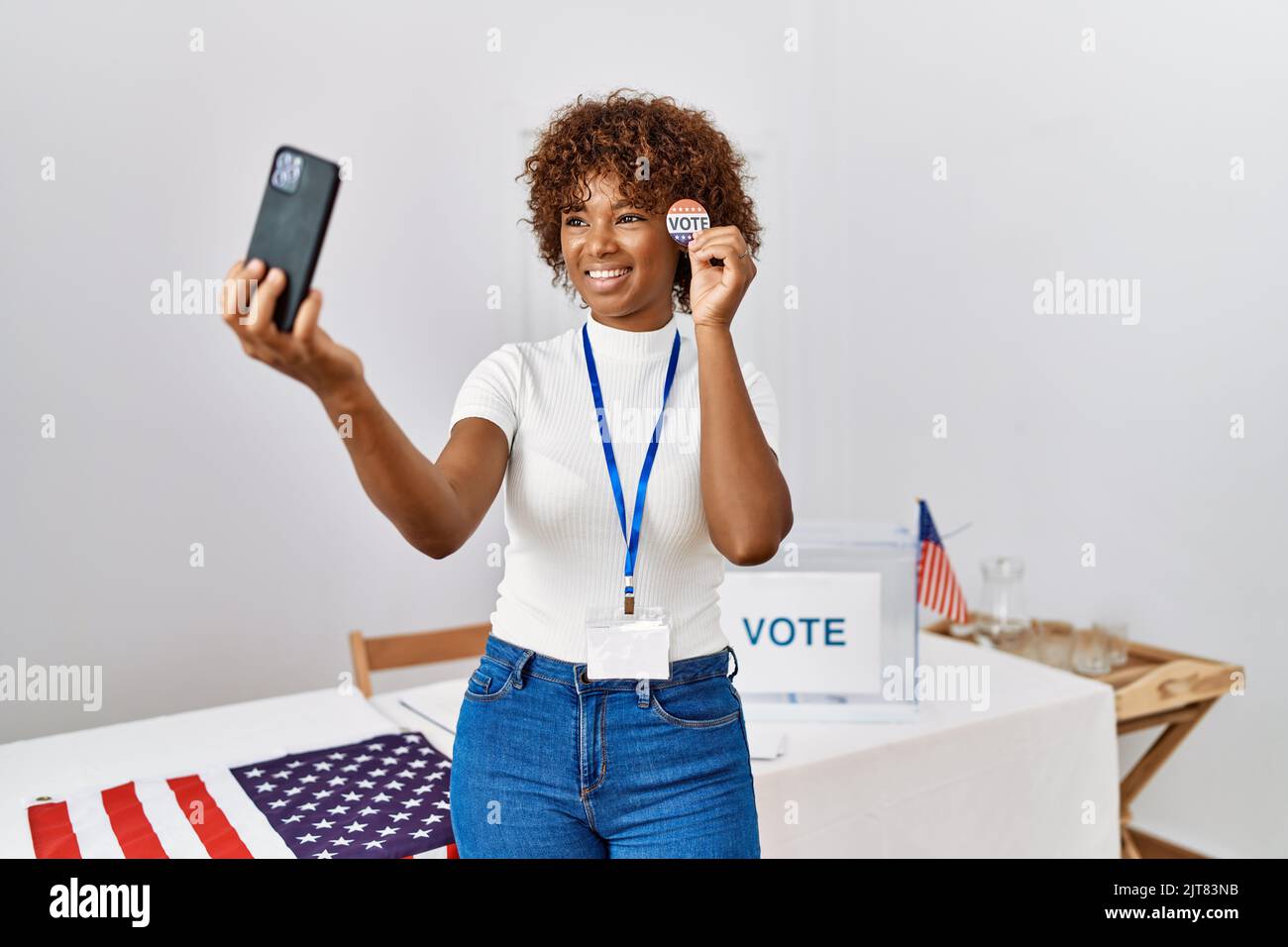 Young african american woman holding badge make selfie by the smartphone at electoral college Stock Photo