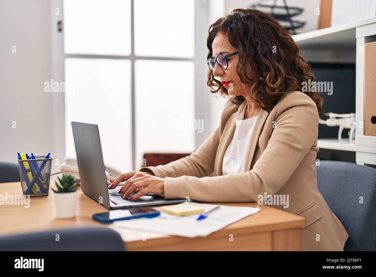 Middle age hispanic woman working with laptop at the office Stock Photo ...