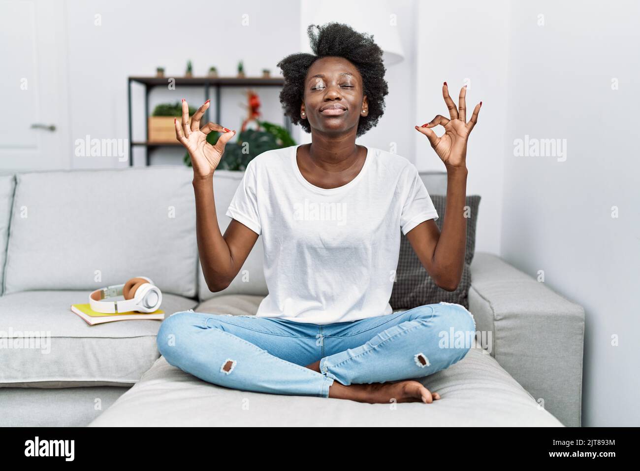 African young woman sitting on the sofa at home relax and smiling with ...