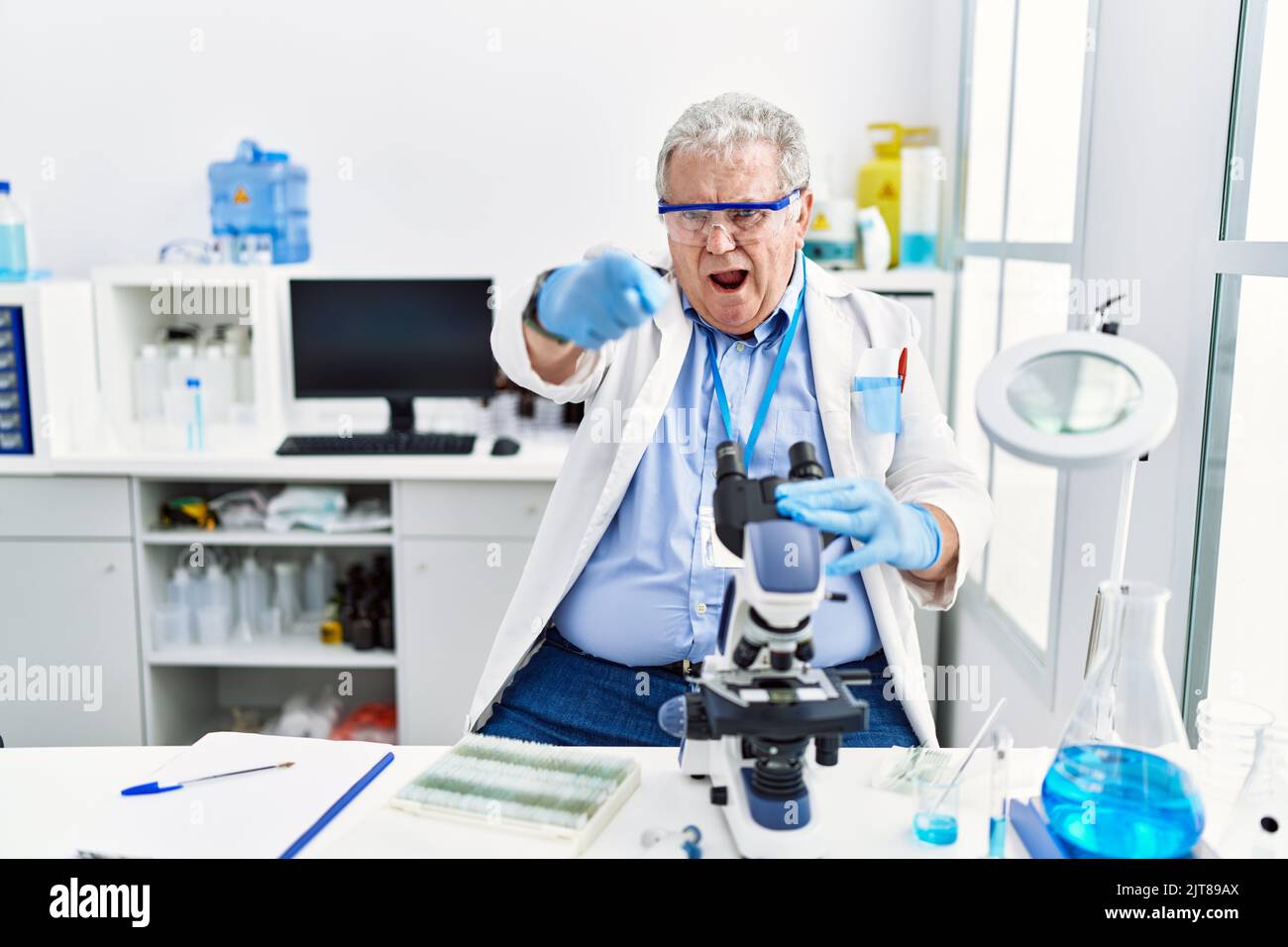 Senior caucasian man working at scientist laboratory pointing ...