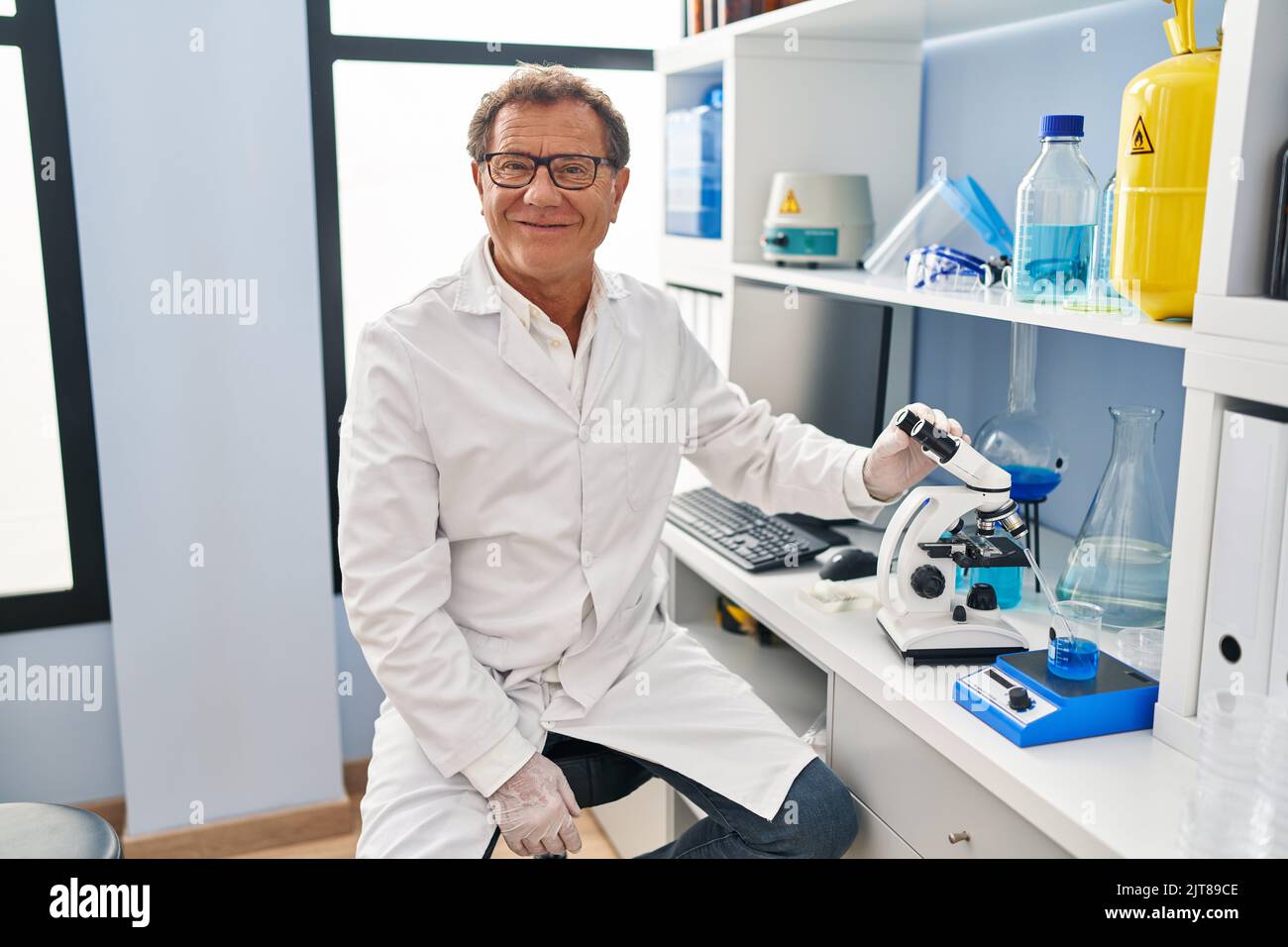 Senior man working at scientist laboratory looking positive and happy ...