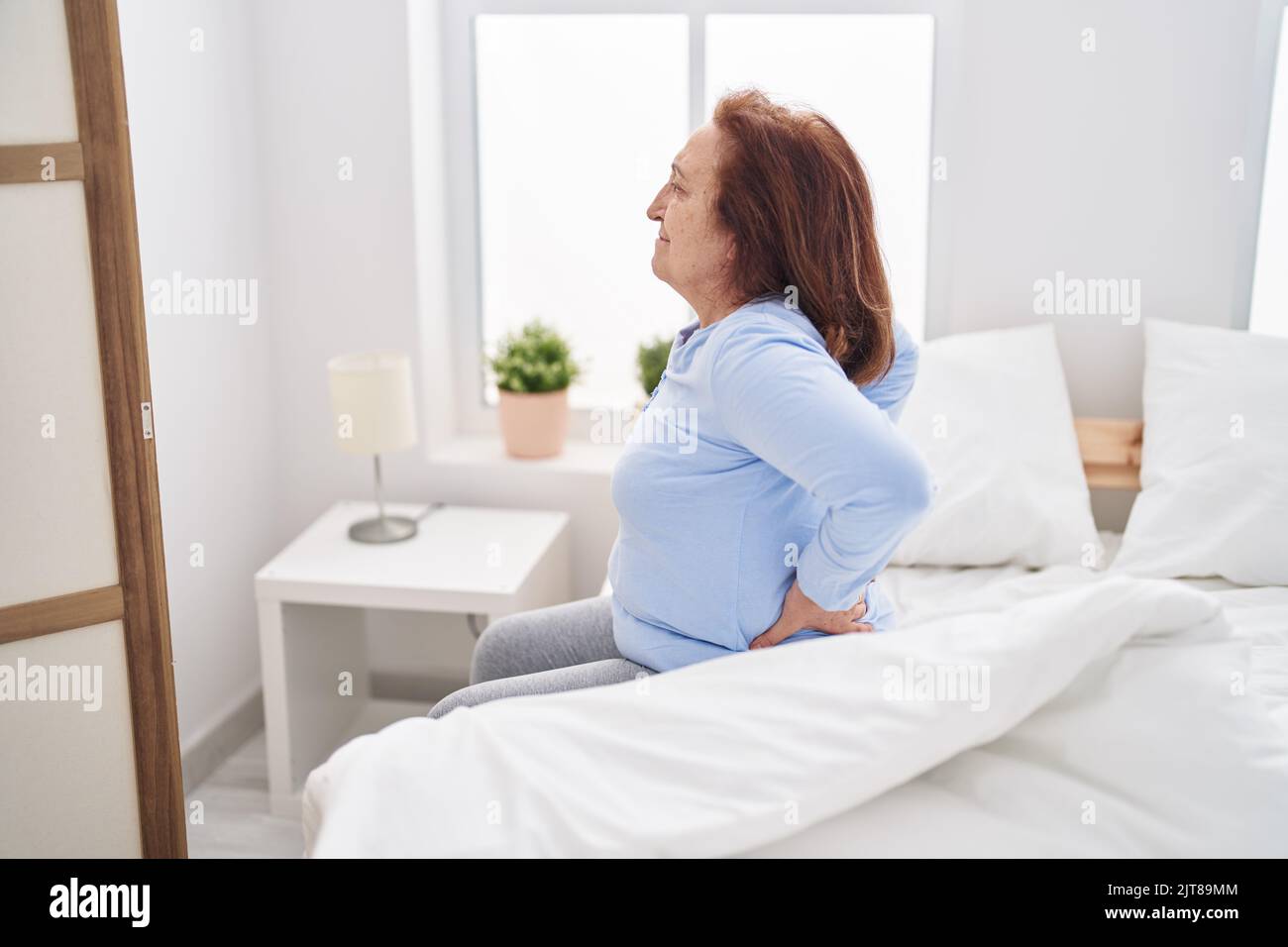 Senior woman suffering for backache sitting on bed at bedroom Stock Photo Alamy
