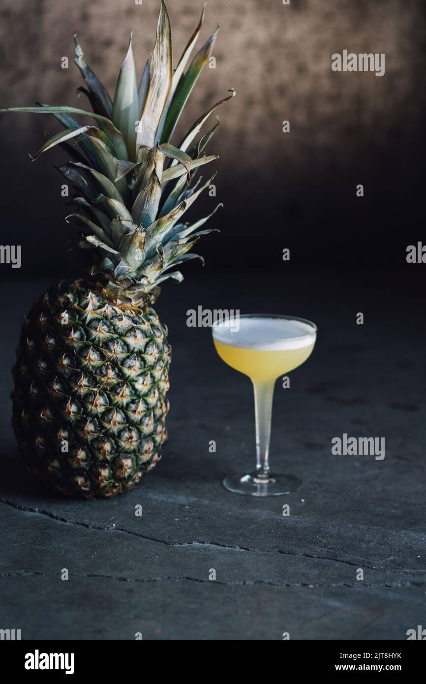 tropical yellow cocktail in hollow stem coupe glass with pineapple ...