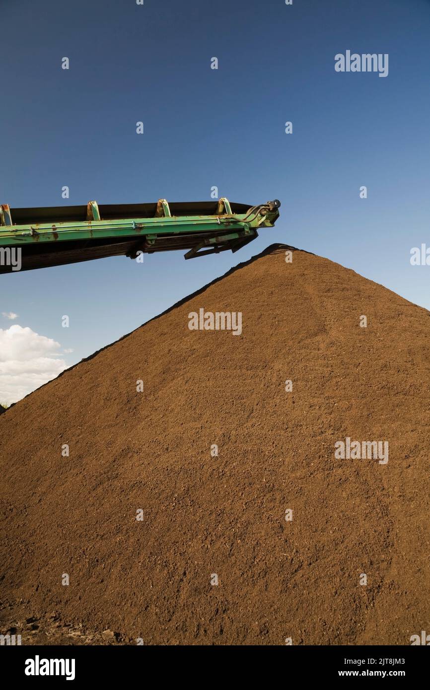 Stacking conveyor and mound of topsoil in a commercial sandpit. Stock Photo