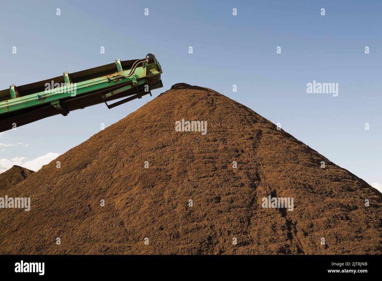 Stacking conveyor and mound of topsoil in a commercial sandpit. Stock Photo