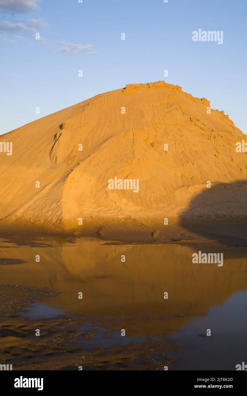 Mound of golden brown sand in a commercial sandpit after a heavy rainfall. Stock Photo