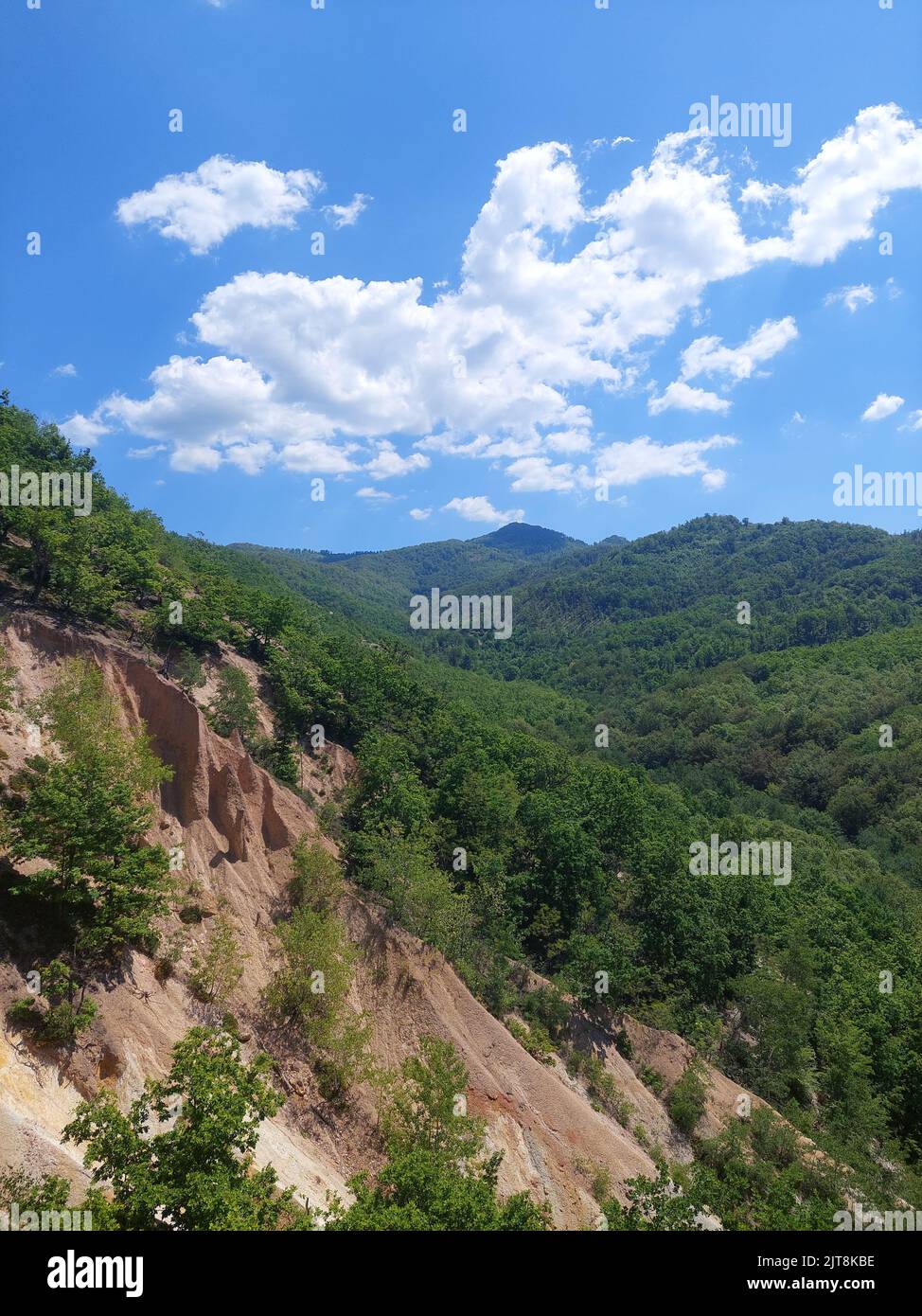 The top of a greenery rocky mountain under blue cloudy sky Stock Photo ...