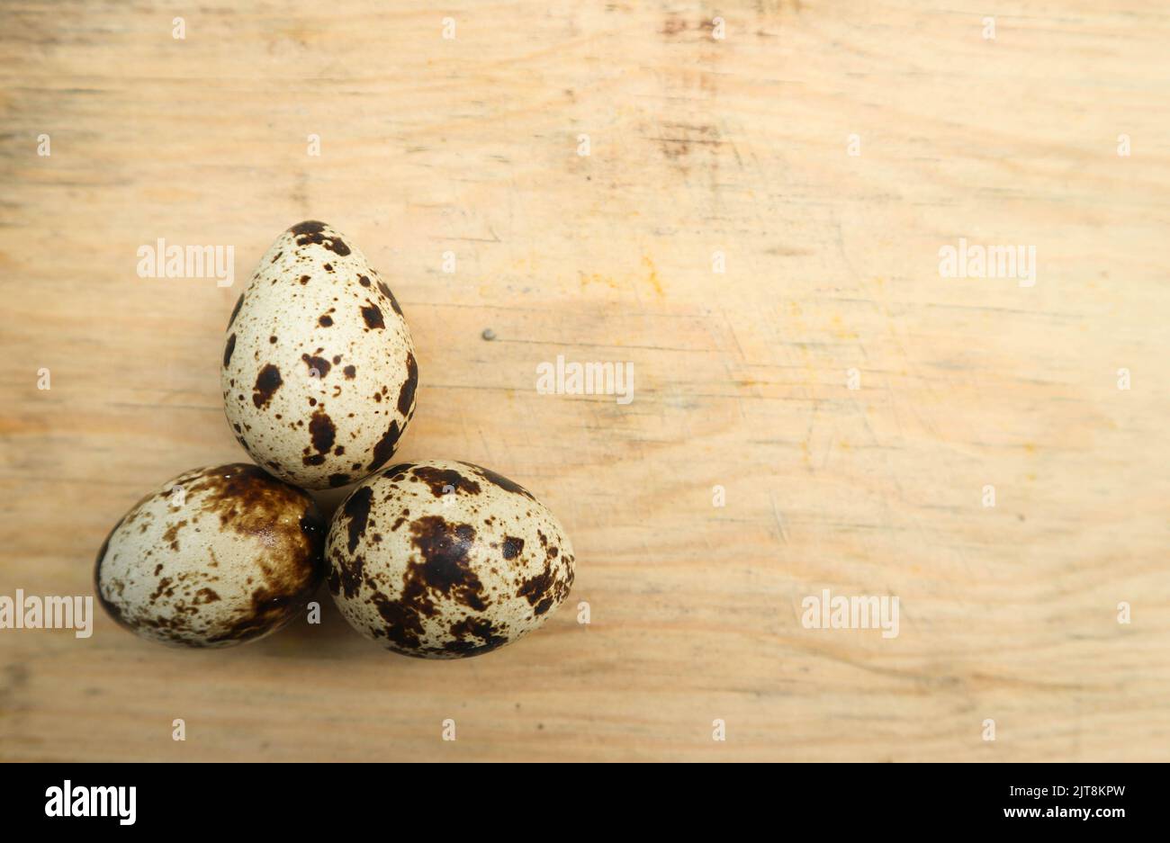 three quail eggs on a cutting board Stock Photo