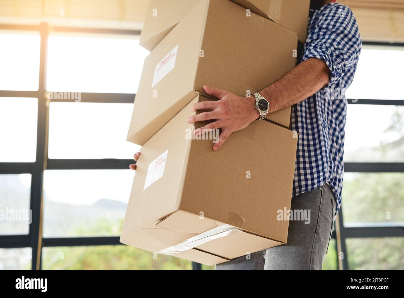 I hope I dont drop this. an unidentifiable man carrying a pile of boxes while moving house Stock