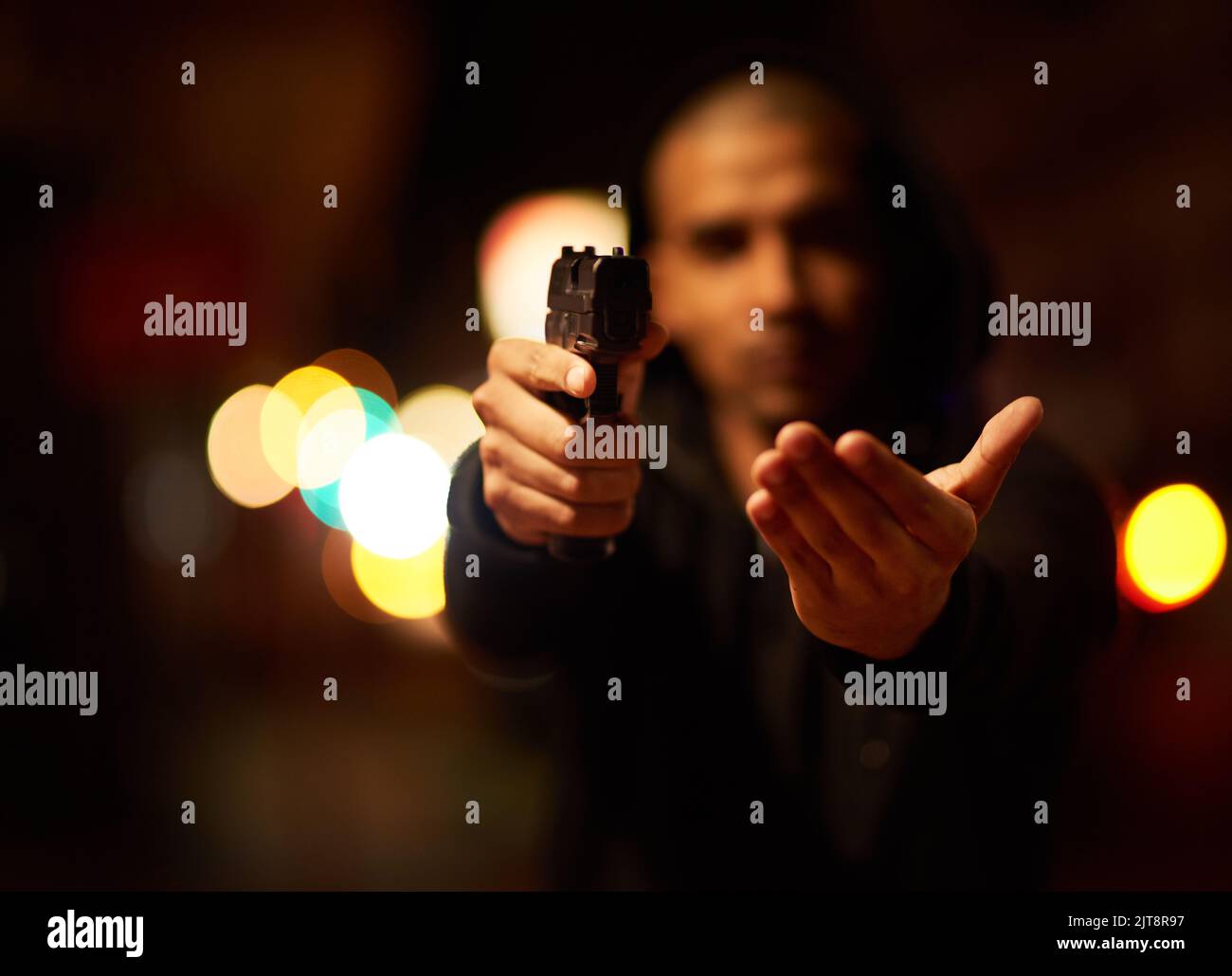 Give it to me. a gun-wielding thief aiming his weapon. Stock Photo