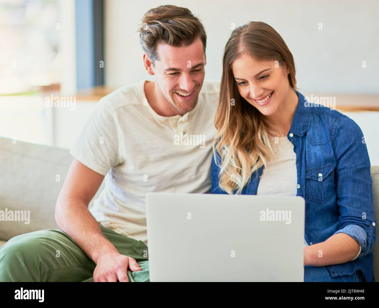 Blogging with her boyfriend. an affectionate young couple using their laptop while sitting on the sofa at home. Stock Photo