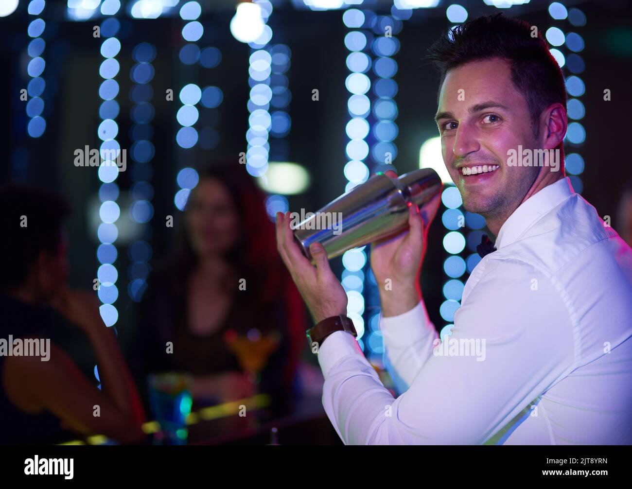 Having fun is all part of the job. Portrait of a smiling bartender mixing a drink behind the bar of a nightclub. Stock Photo