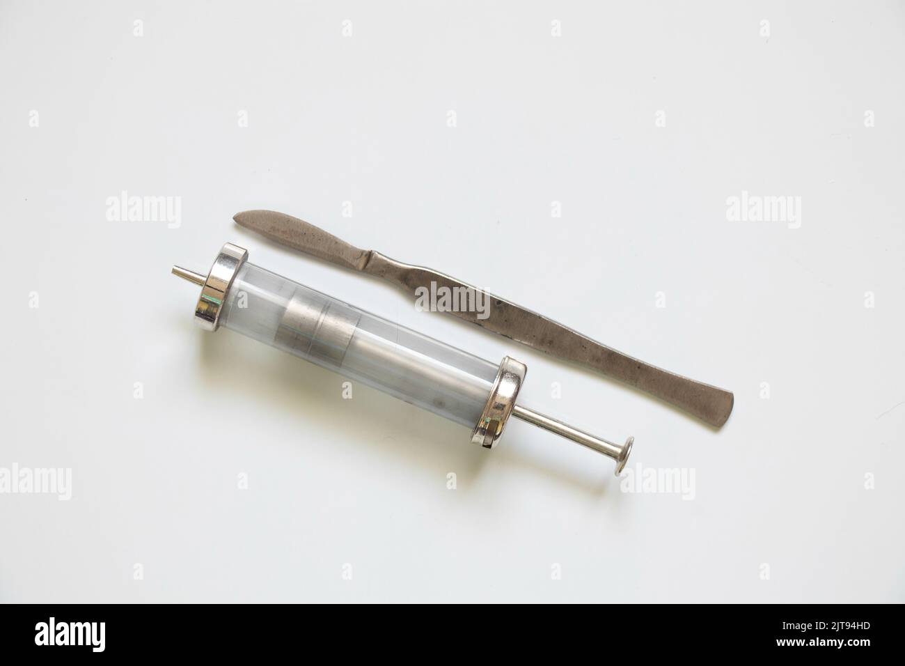 old reusable syringe and scalpel on a white background, medical equipment Stock Photo