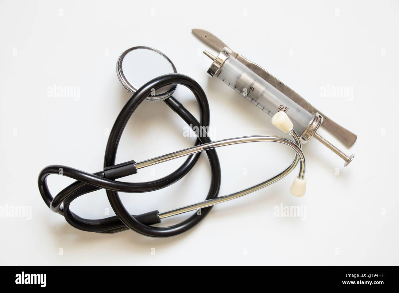 Stethoscope old syringe and scalpel lie on a white background ,medical instruments close-up Stock Photo