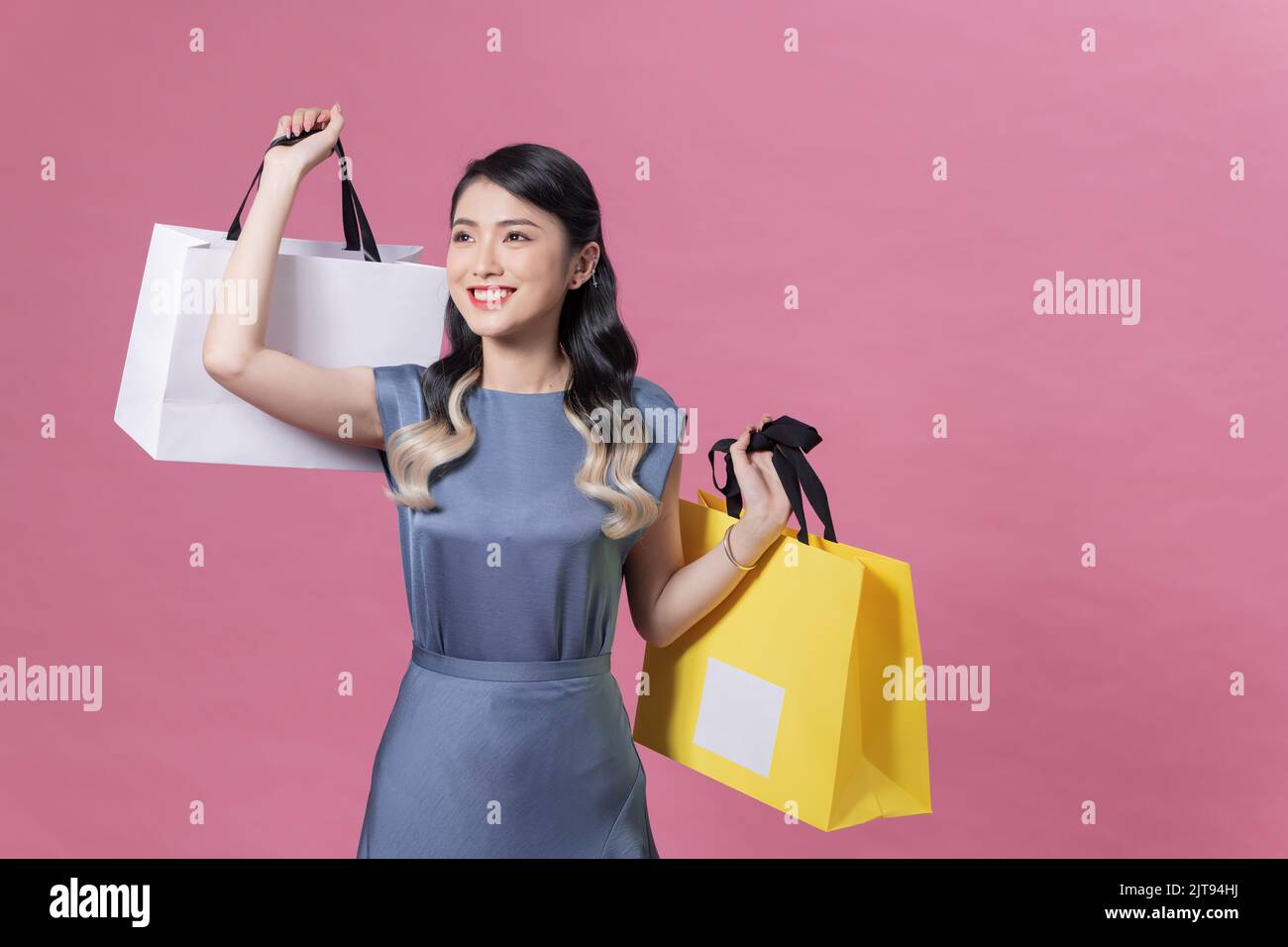 Beautiful young woman with shopping bags on color background Stock Photo