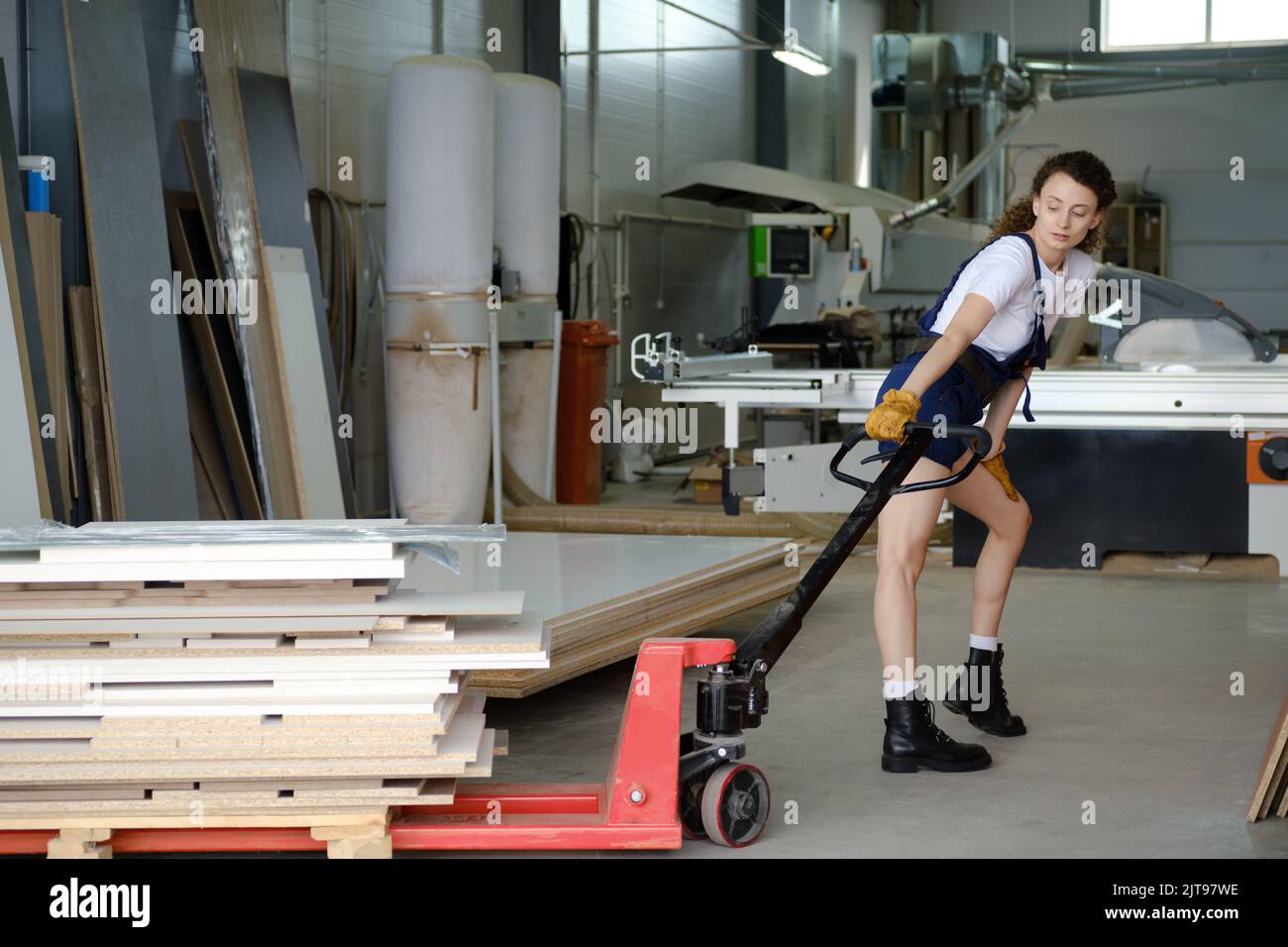 Young woman using hydraulic trolley in carpenter workshop Stock Photo