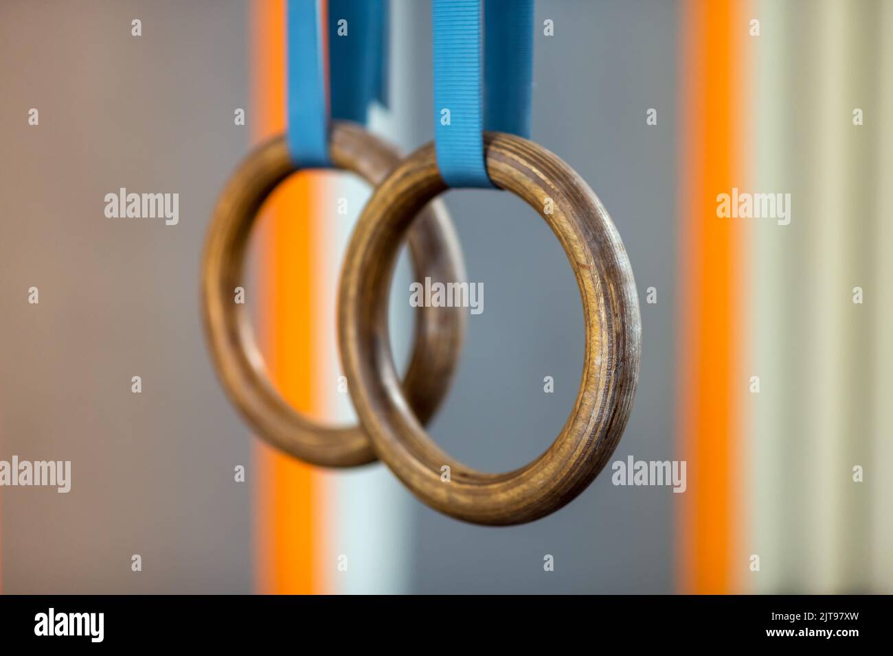 Soft focus of steady gymnastic rings hanging on blue belts during