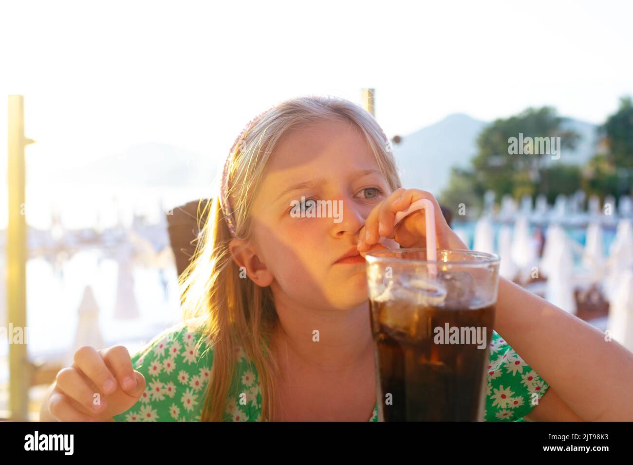Little girl drinking soda with a straw in outdoor cafe Stock Photo