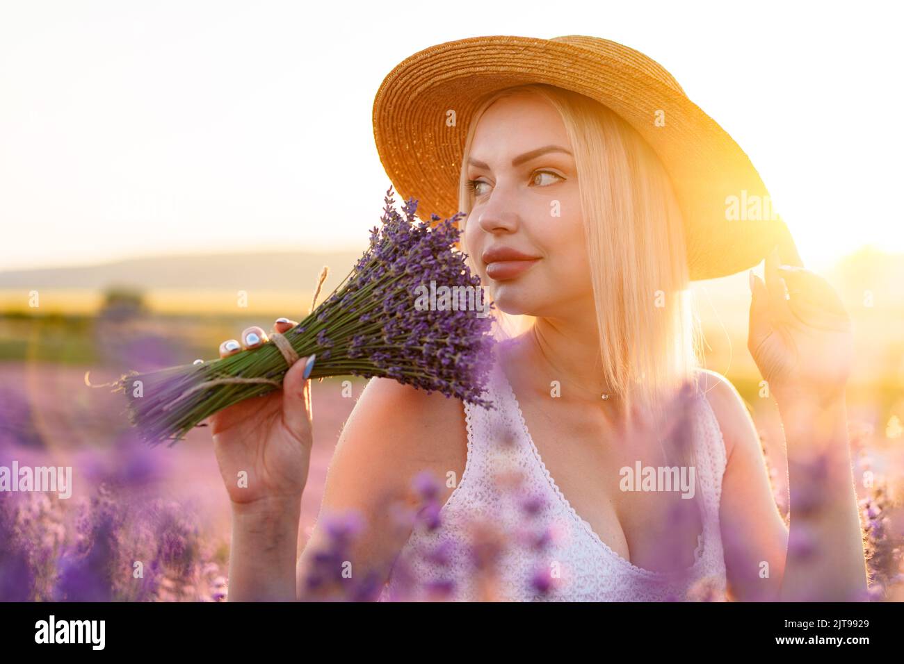 Portrait o charming blonde girl smells lavender flowers in lavender
