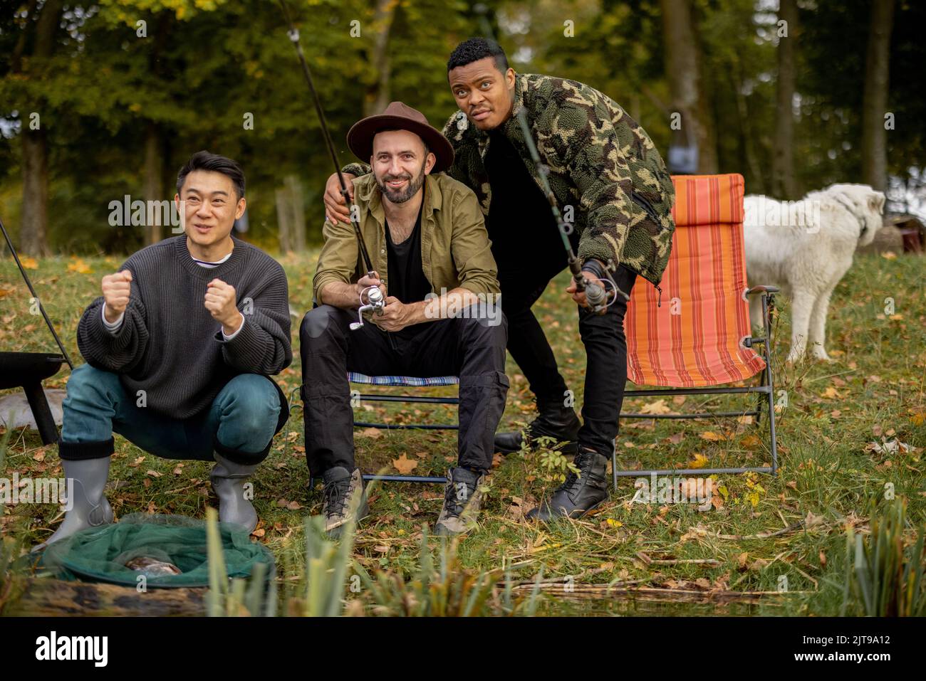 Pleased male friends resting and fishing in nature Stock Photo