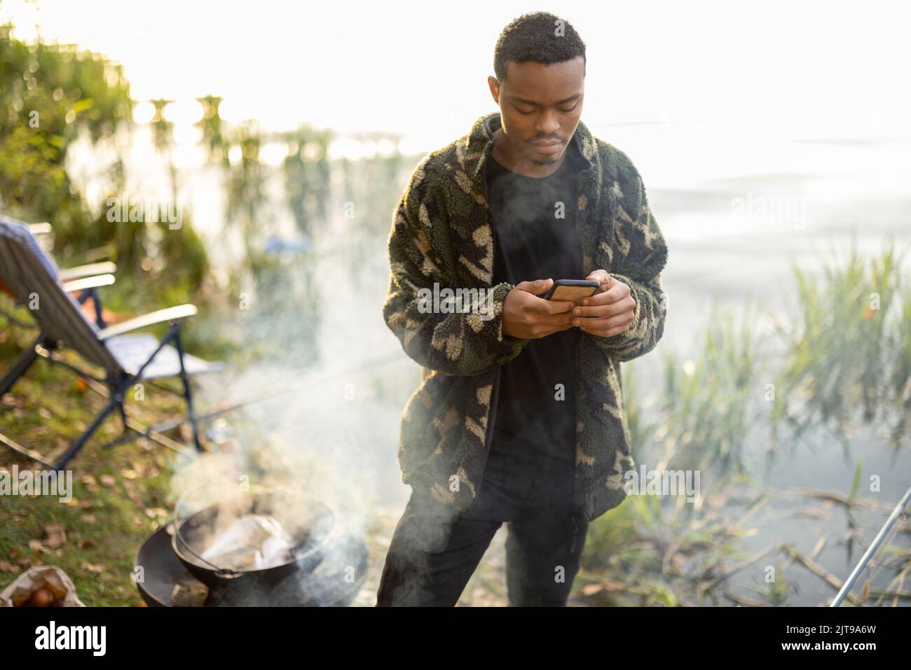 Men using smartphones during resting on pond coast Stock Photo