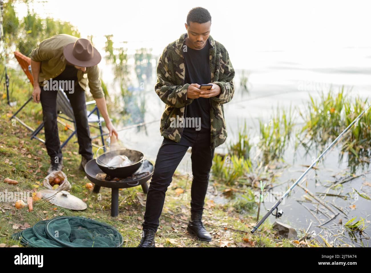 Men using smartphones during resting on pond coast Stock Photo