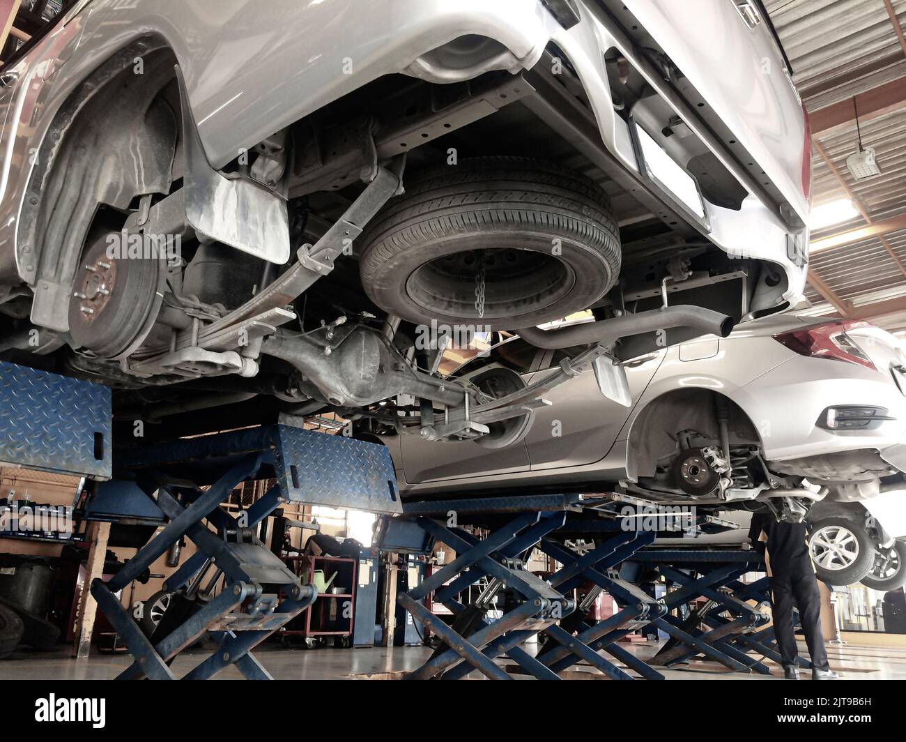 Pickup truck and sedan car in the process of changing wheels on the car lifts in a garage. Focus on the wheel hub. Stock Photo