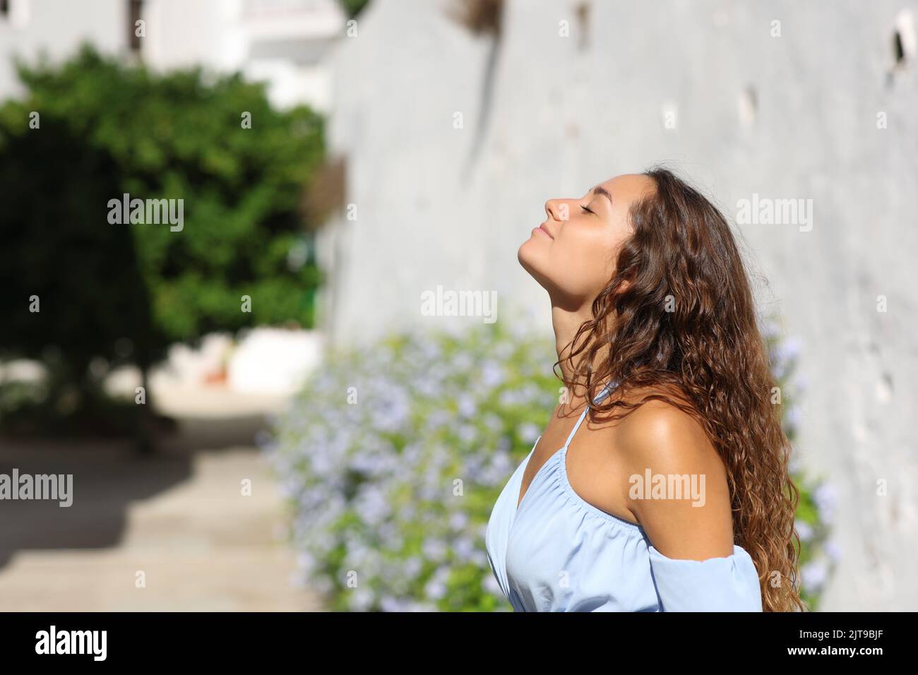 Side view portrait of a woman breathing fresh air in a white town street Stock Photo