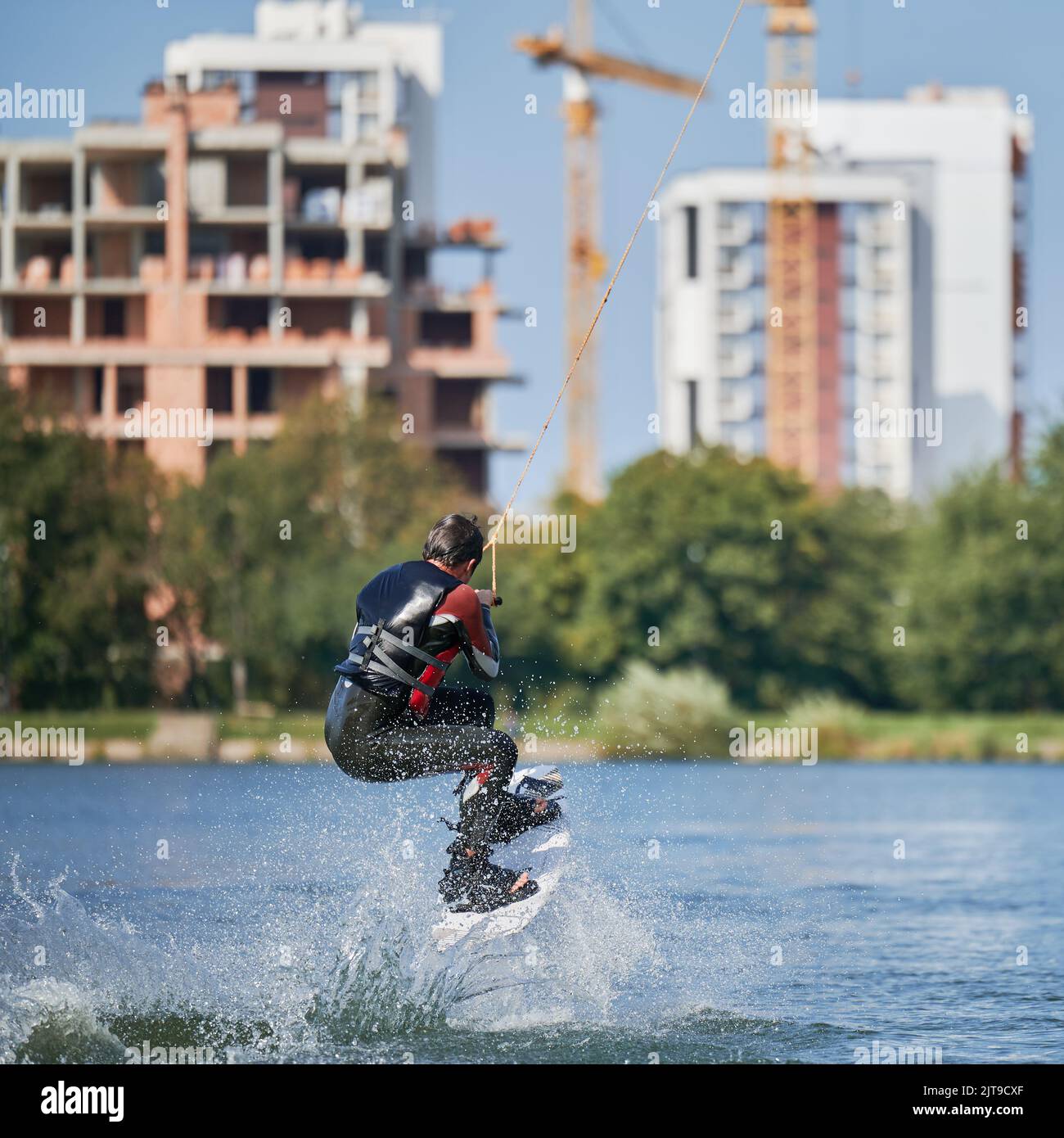 Wakeboarder surfing on lake. Young man surfer having fun wakeboarding