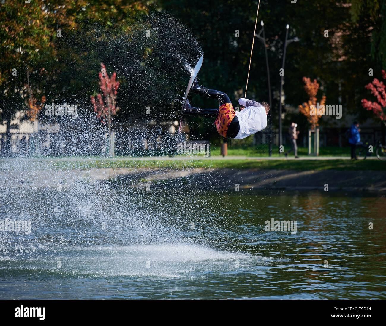 Wakeboarder making tricks while wakeboarding on lake. Young man surfer having fun wakesurfing in