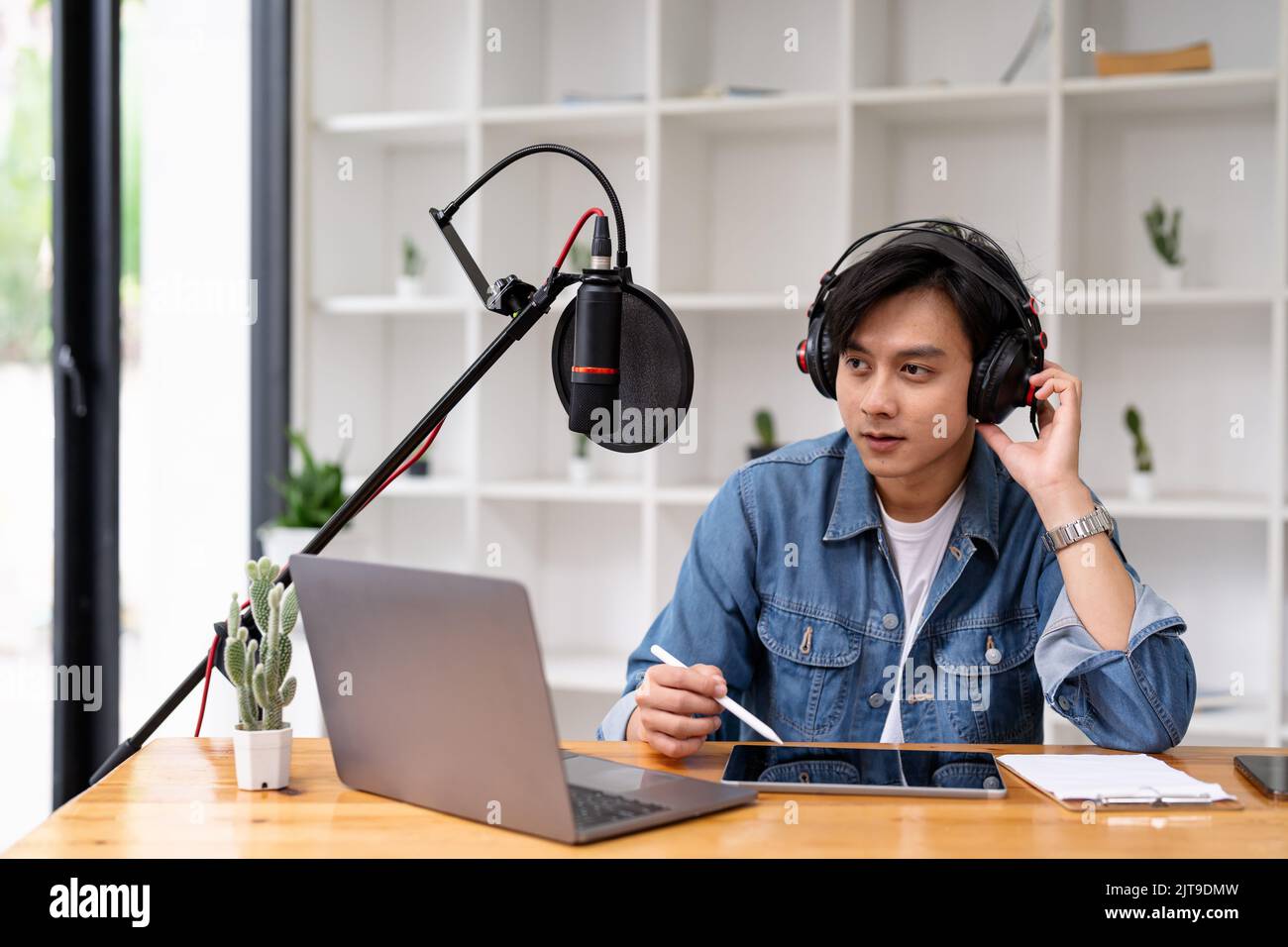 Asian man recording a podcast on laptop computer with microphone while