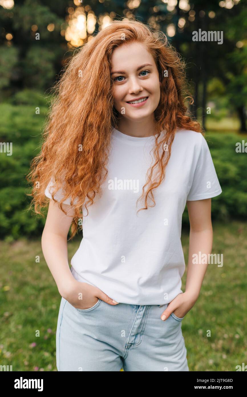 Happy ginger girl generation z smiling on camera while posing outdoor