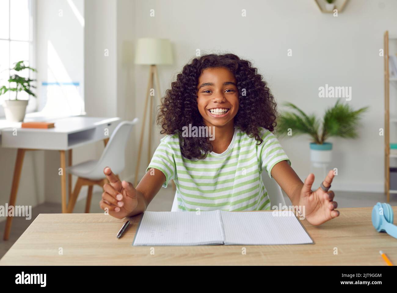Portrait of happy African American school girl sitting at desk, looking ...