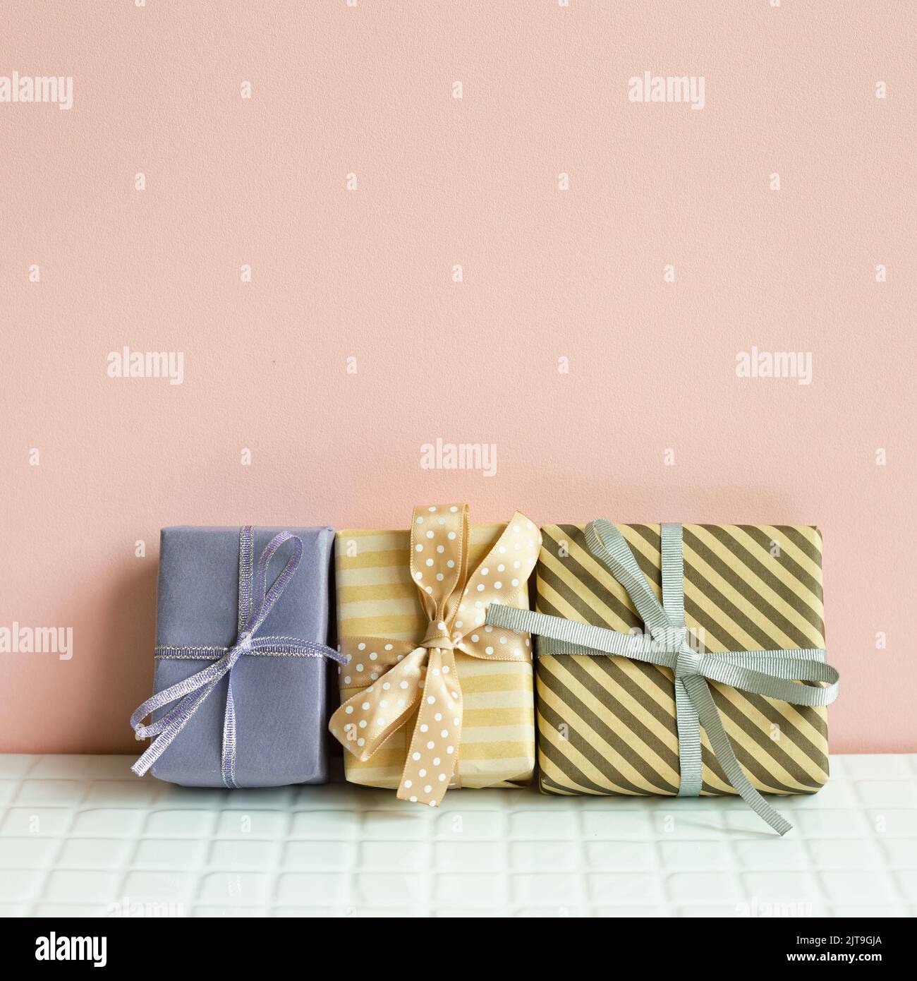 Colorful gift boxes on white table. pink wall background Stock Photo