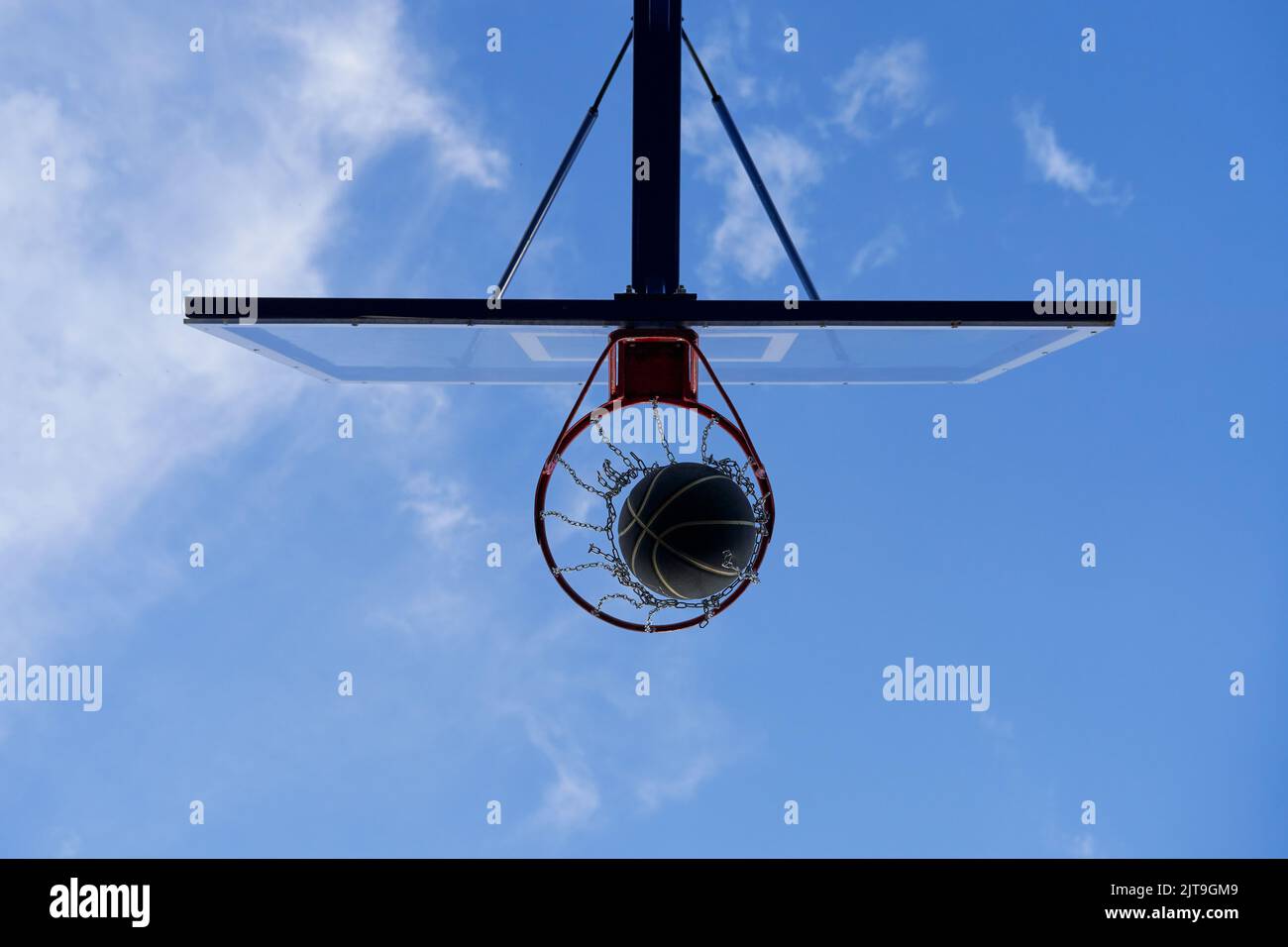 Street basketball ball falling into the hoop. Close up of black ball in