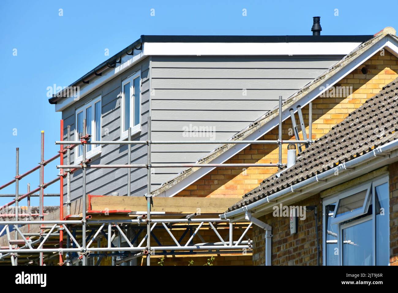 Scaffolding around almost finished new dormer flat roofed extension built into pitched roof on back elevation to semi detached house Essex England UK Stock Photo