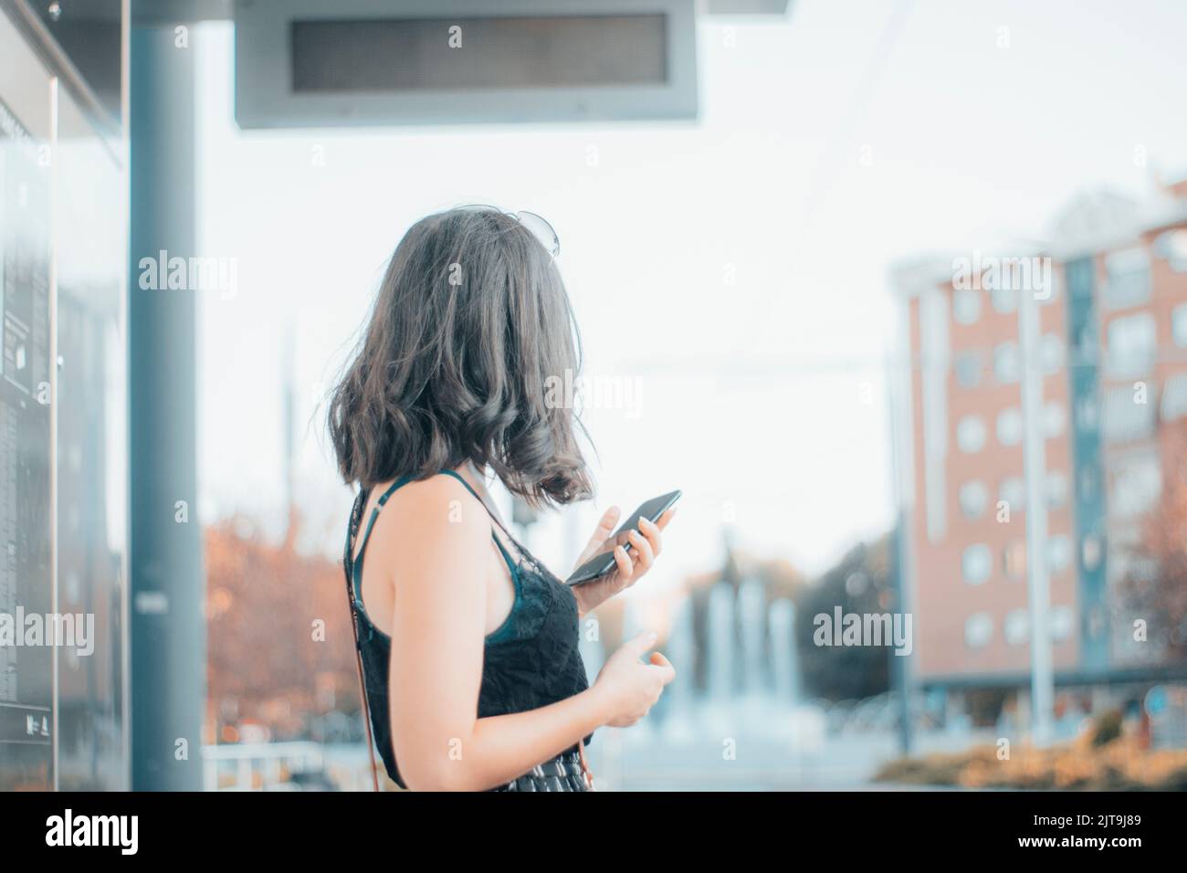 A Caucasian female model waiting at a bus station Stock Photo - Alamy