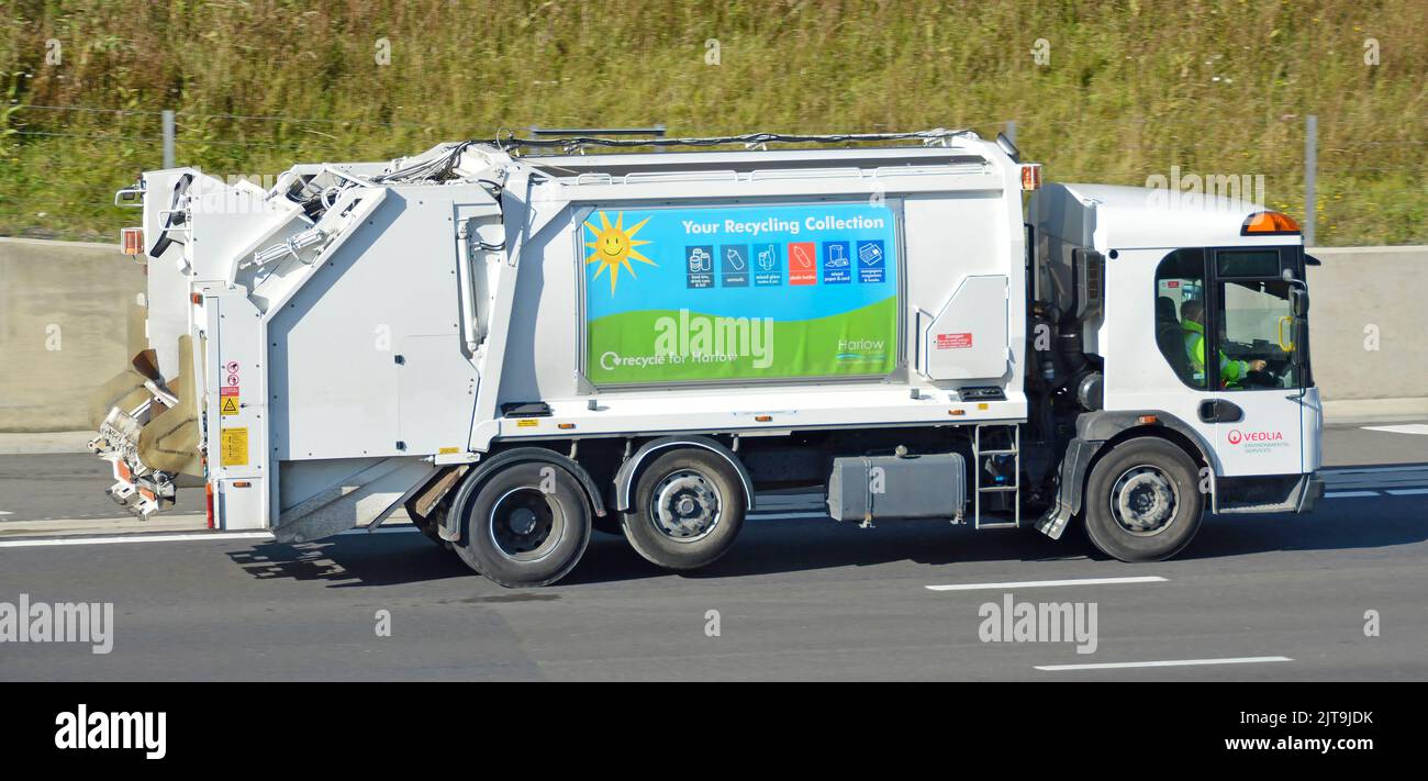 Veolia side roof view white clean environmental services garbage rubbish refuse dustcart bin lorry truck with driver driving along UK motorway road Stock Photo